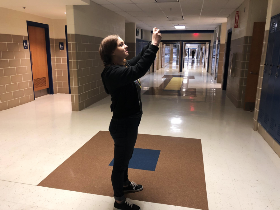 Senior Brianna Katauskas, stops to take photo of art above lockers for journalism photo caption practice Tuesday during second period. The Journalism class often utilizes sources outside the classroom for more engaging learning.