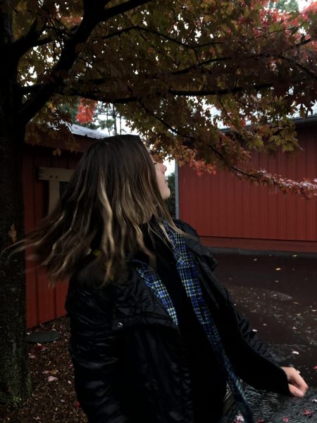 Junior Kotrina Dzindzaleta poses under a tree during a rainy fall day at Bengston's Pumpkin patch.