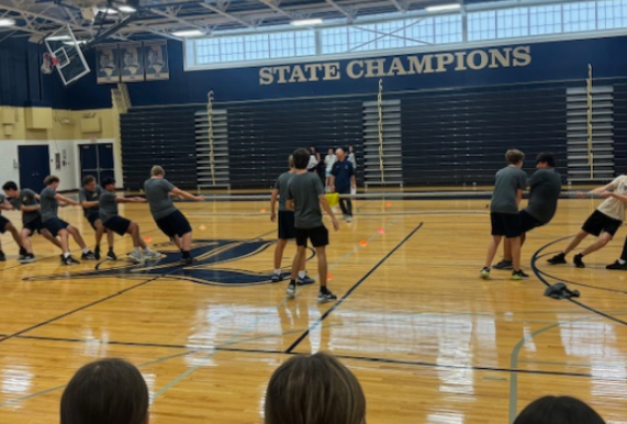 Students in P.E. struggling in a game of tug-of-war.

