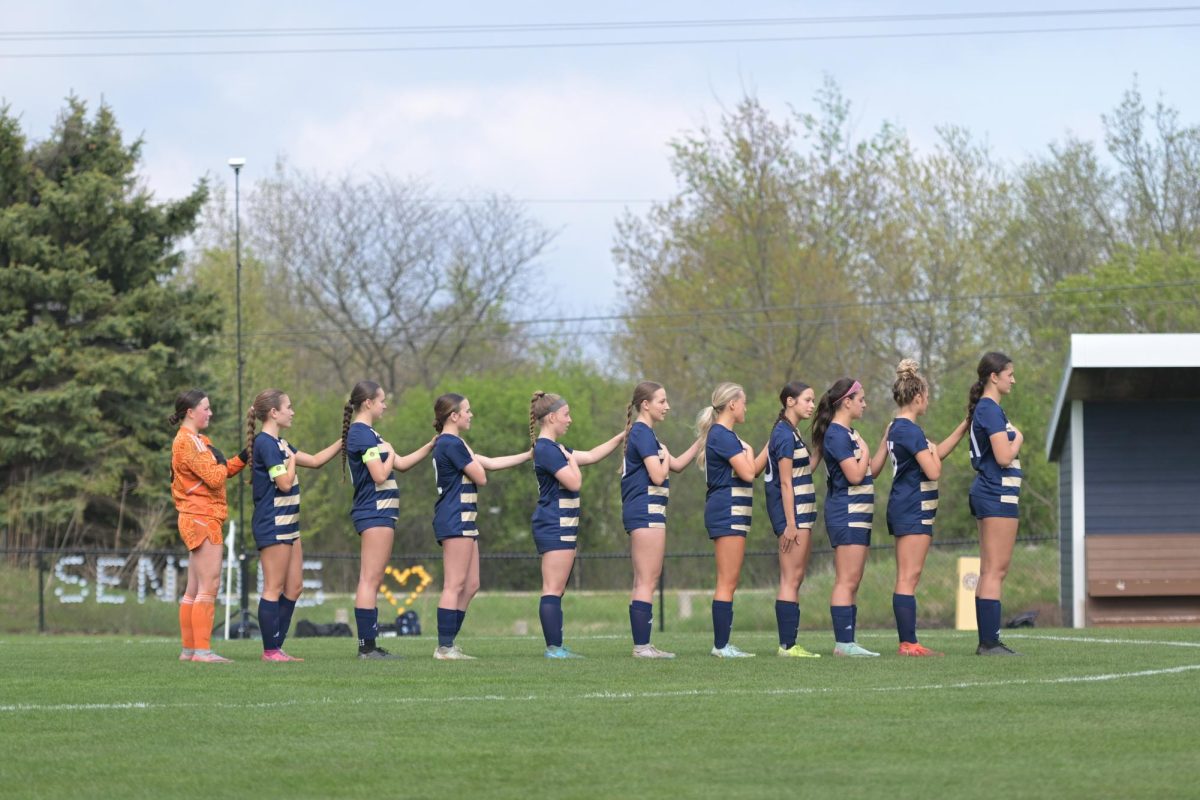 The girls soccer team lines up on the field before a game. 