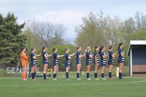 The girls soccer team lines up on the field before a game.